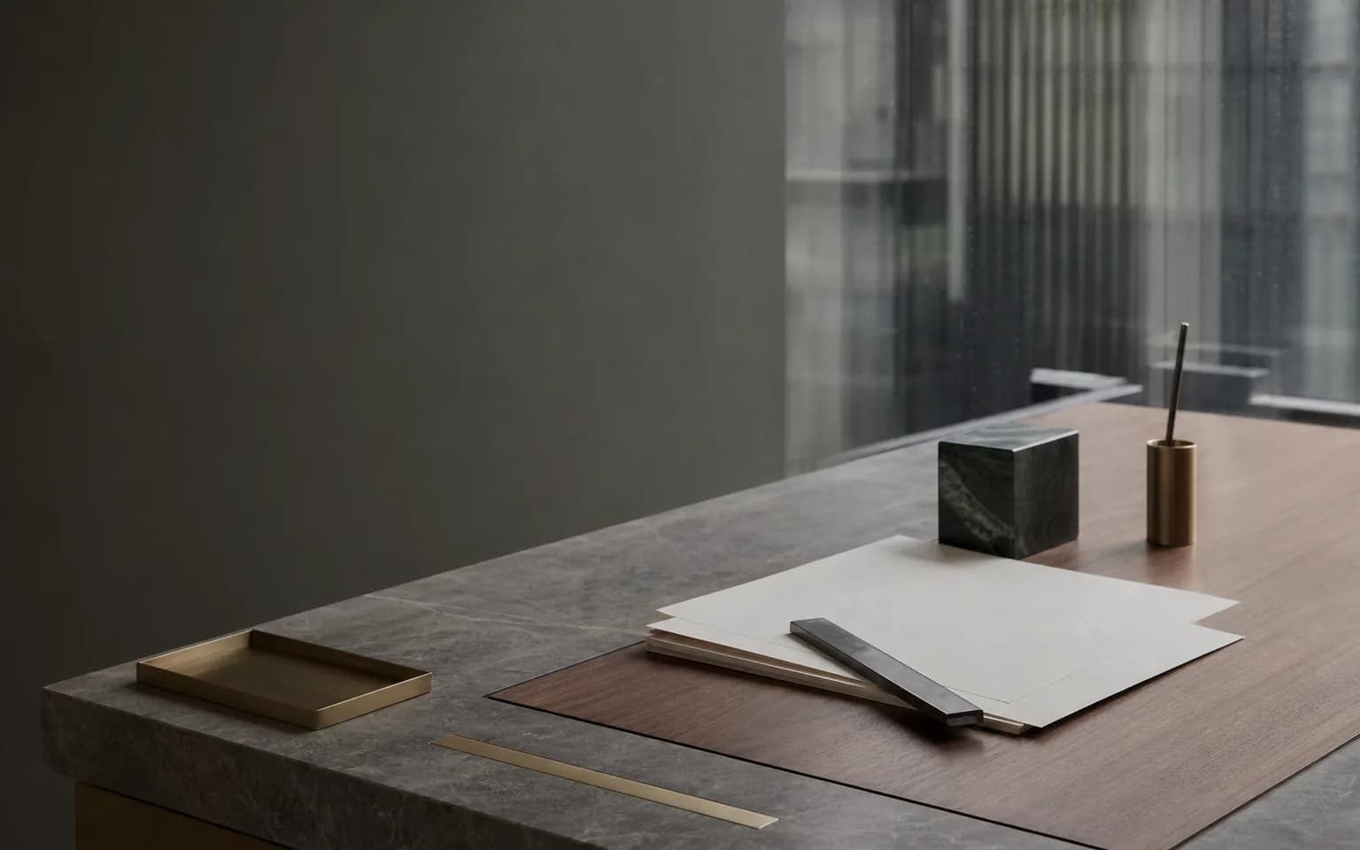 Blank papers, a straightedge, and precise architectural details on a stone and walnut worktable