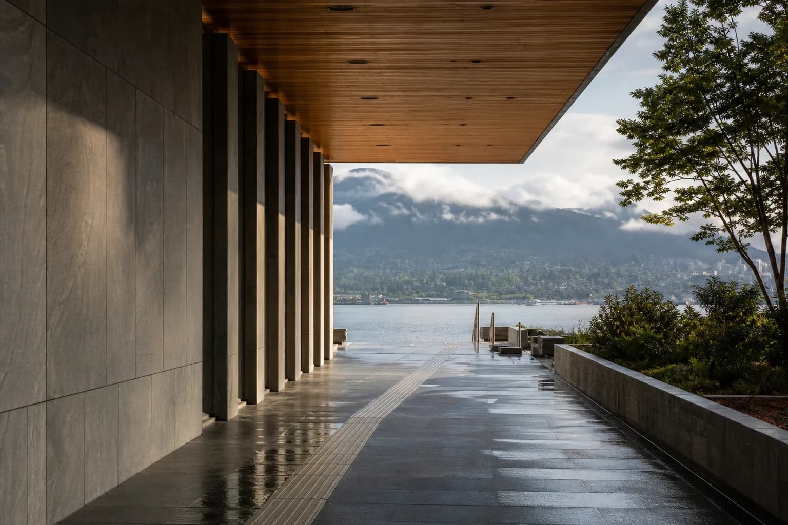 A covered walkway opening toward a calm coastal horizon after rain
